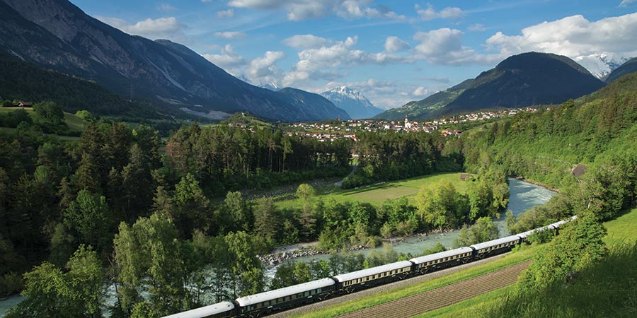 The Venice Simplon-Orient-Express travels through lush green scenery. 